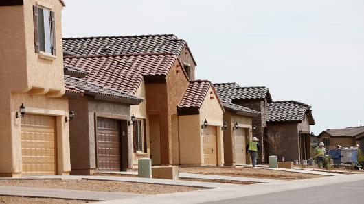 Workers stand in front of a row of new homes at the Pulte Homes Fireside at Norterra-Skyline housing development in Phoenix, Arizona