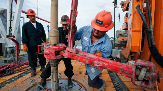 Workers make a pipe connection on the drill string on the Orion Perseus drilling rig that is currently drilling for oil and gas in the Eagle Ford Shale, Webb County, Texas.