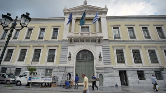 A man walks by the National Bank of Greece headquarters in Athens.