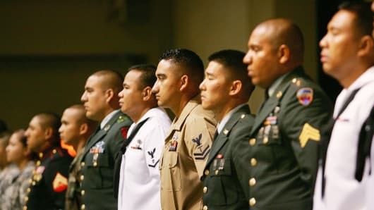 Service members rise after being sworn in as citizens during naturalization ceremonies.