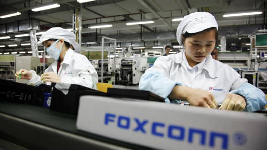 Foxconn employees on the assembly line in Longhua, Shenzhen, China. The company reportedly employed students working overtime at its iPhone factory in Zhengzhou.
