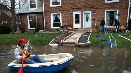Octavio Castillo paddles a boat down a street to reach his cousin's home in Des Plaines, Ill., on April 19.