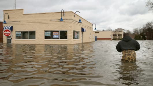 Reyes Garcia wades through floodwater to inspect flood damage to a building April 19, 2013 in Des Plaines, Illinois.