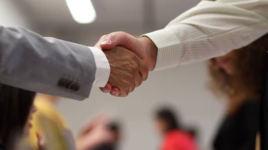 A job seeker (R) shakes hands with a recruiter.