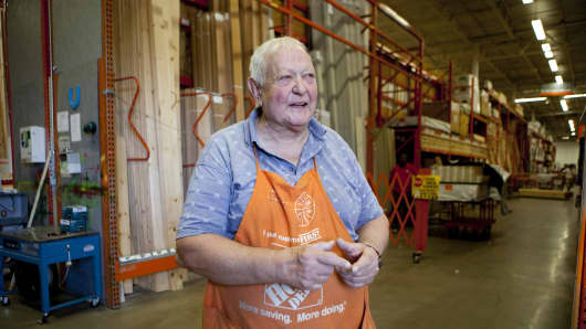 A senior citizen works as a sales associate at Home Depot in the lumber department.