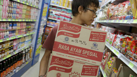 A shopper picks up two boxes of PT Indofood at a supermarket in Jakarta.