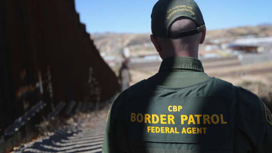 A U.S. Border Patrol agent looks at a section of the U.S. - Mexico border.