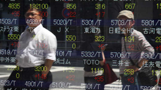 Pedestrian are reflected in an electronic stock board in Tokyo, Japan, on Friday, May 24, 2013.