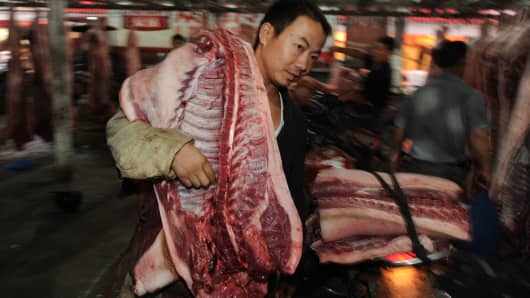 A vendor carries a slaughtered pig at a market in Hefei, China, on September 17, 2011.