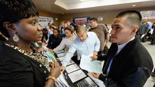 Job seekers pick up fliers adverising jobs during Los Angeles Mission's 12th annual Skid Row Career Fair on June 6, 2013 in Los Angeles, California