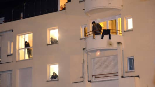 Migrants look at their windows in a former retirement house while gendarmes prepare to evacuate them