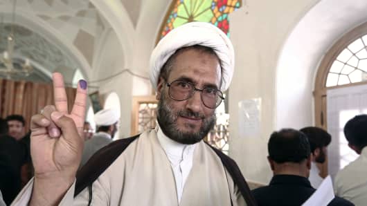 An Iranian clergyman shows his ink-stained finger after voting in the first round of the presidential elections in the Islamic Republic at a polling station at the Massoumeh shrine in the holy city of Qom on June 14, 2013.