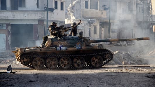 Syrian army troops drive through the ravaged streets of Qusayr in the central Homs province on June 5, 2013, after government forces seized total control of the former rebel-stronghold.