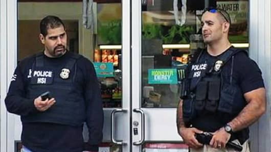 Police officers stand outside one of the several 7-Elevens they raided as part of an identity theft and illegal immigration investigation.