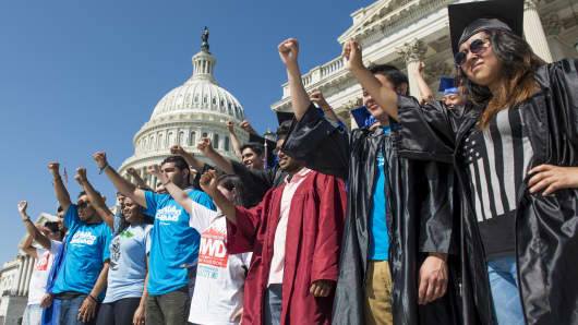 Members of United We Dream, an immigrant youth-led organization, wearing caps and gowns hold their fists in the air on the steps of the Senate to call for immigration reform.