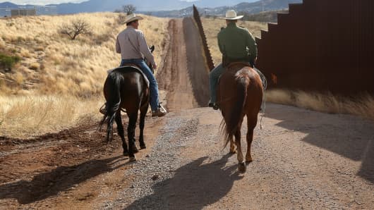 A U.S. Border Patrol agent rides with a cattle rancher at the U.S.-Mexico border.