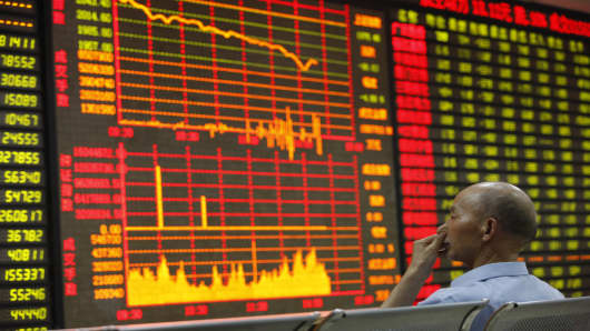 An investor watches the electronic board at a stock exchange hall in Huaibei, China.
