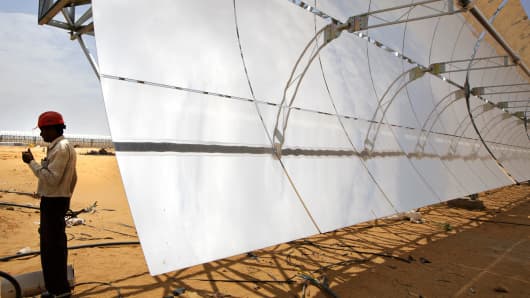 A worker stands beside a parabolic trough at the Godawari solar-thermal power plant, near Nokh, Rajasthan, India, June 10, 2013.