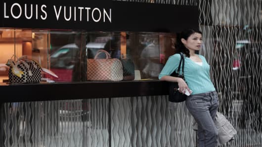 A Chinese woman leaning on a Louis Vuitton shop display window in Hong Kong.