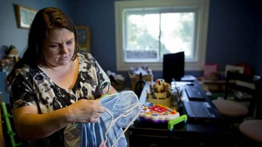 Mary Conti sorts through her daughter's princess dresses before listing them for sale on a consignment website. Conti thinks it's still possible to climb the economic ladder, but it takes both luck and hard work.