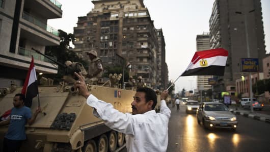 Egyptians salute army vehicles upon their deployment on a street leading to Cairo University on July 3, 2013.