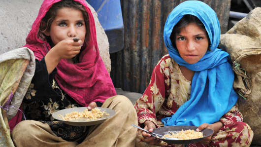 Afghan children, who salvage recyclable items from garbage to make a living, eat a meal of rice in Jalalabad on June 30, 2013.