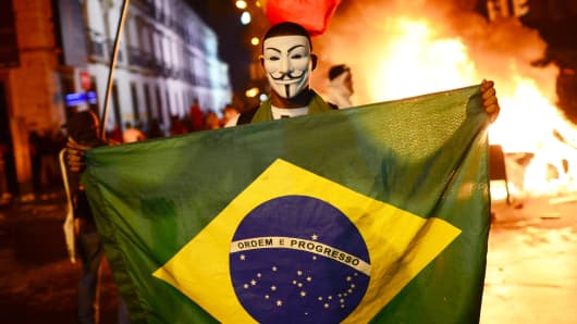 A demonstrator wearing a Guy Fawkes mask is seen during clashes in downtown Rio de Janeiro, after a protest over higher transportation fares.