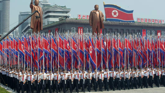 North Koreans wave flags and walk with statues of former leaders Kim Il-Sung and Kim Jong-Il during a military parade past Kim Il-Sung square marking the 60th anniversary of the Korean War armistice in Pyongyang on July 27, 2013.