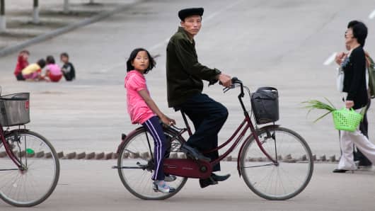 A father and daughter on a bicycle in Rajin, North Korea.