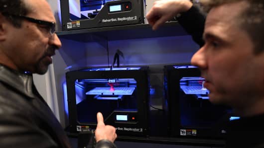 Visitors look at a 3D printer printing an object, during 'Inside 3D Printing' conference and exhibition in New York.