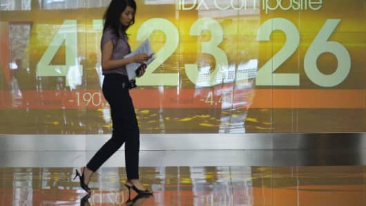 A woman walks past an Indonesian stock exchange display board in Jakarta on August 20, 2013.