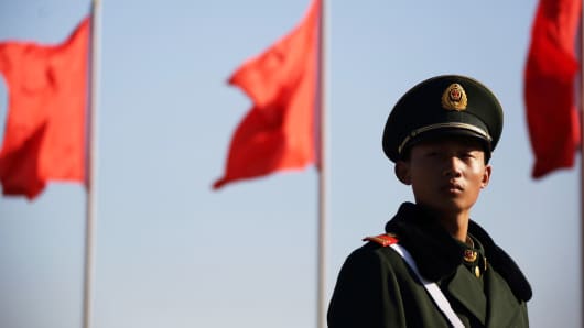 A paramilitary police officer stands guards in front of flags at Tiananmen Square in Beijing.