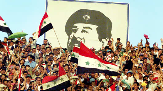 Baghdad residents cheer under an image of President Saddam Hussein in 2001.