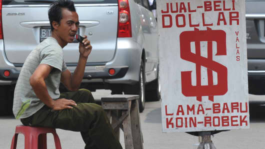 An Indonesian man waits for customers at a street money changer in Jakarta on August 28, 2013.