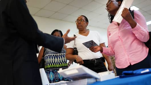 Job seekers speak with an employment recruiter in Brooklyn, NY