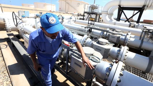A file photo showing a Libyan oil worker from the Libyan National oil and gas company checks an oil pipelines at the Zawiya oil installation in Zawiya, Libya.