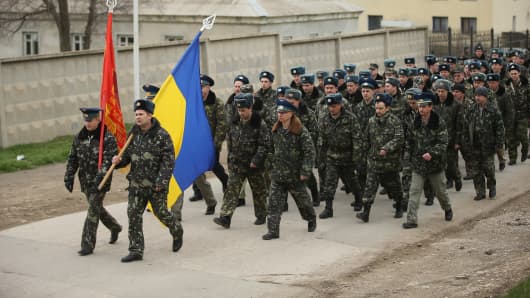 Unarmed Ukrainian troops bearing their regiment and the Ukrainian flags march to confront soldiers under Russian command occupying the Belbek airbase in Crimea on March 4, 2014 in Lubimovka, Ukraine.