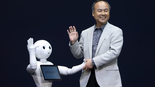 Billionaire Masayoshi Son, chairman and chief executive officer of SoftBank Corp., shakes hands with a human-like robot called Pepper, developed by the company's Aldebran Robotics unit, during a news conference in Urayasu, Chiba Prefecture, Japan.