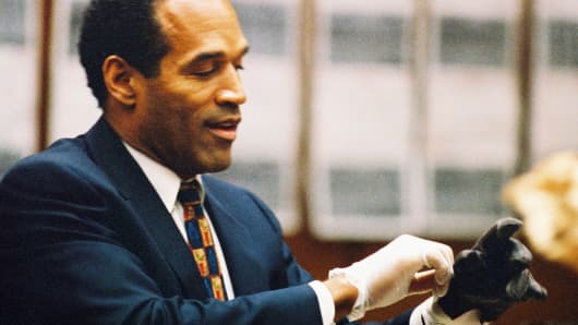 O.J. Simpson tries on a leather glove allegedly used in the murders of Nicole Brown Simpson and Ronald Goldman during testimony in Simpson's murder trial on June 15, 1995 in Los Angeles.