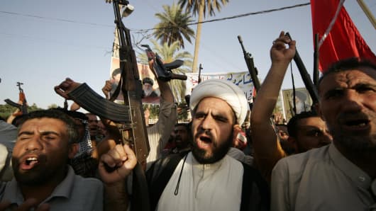 Tribal fighters shout slogans while carrying weapons during a parade in Kerbala, south of Baghdad, June 18, 2014.