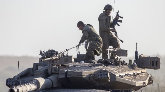 Israeli soldiers stand on their Merkava tank on july 17, 2014 at an army deployment area near Israel's border with the Gaza Strip.