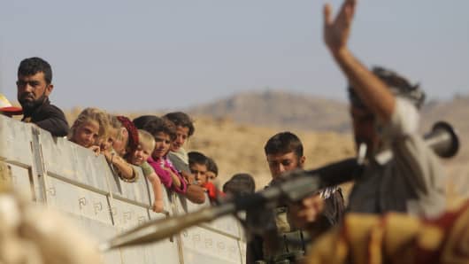 A Yazidi fighter who recently joined the Kurdish People's Protection Units gestures while securing a road in Mount Sinjar, August 13, 2014.