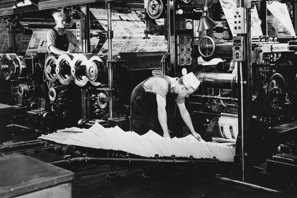 Pressmen operate a newspaper press in this circa 1940 photo.