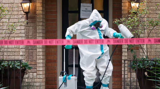 A member a HazMat team disinfects the entrance to the home of the Texas nurse who contracted Ebola from a patient.