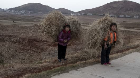 North Korean children carry hay on a road near Mount Kuwol in South Hwanghae province, North Korea.