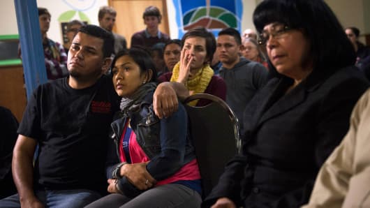 Undocumented immigrant Angela Navarro and her husband Ermer Fernandez (L), along with other immigrants and supporters, watch President Barack Obama announce executive action on immigration, at the West Kensington Ministry church, in Philadelphia, Nov. 20, 2014.