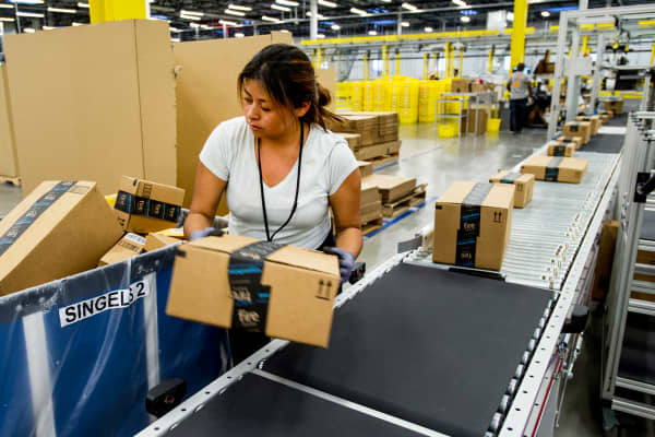 An Amazon.com Inc. employee lifts a box from a conveyor at the company's fulfillment center in Tracy, California