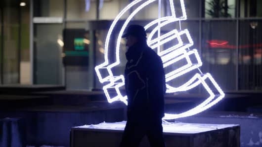 A man walks by a euro sign light installation in Vilnius, Lithuania, on December 31, 2014.
