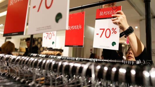 An employee adjusts a discount sign in a department store in Paris, January 6, 2015.