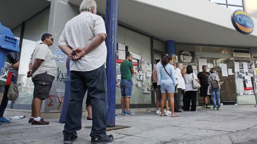 Job seekers wait in a line to enter an employment center before opening in Athens, Greece, Sept. 10, 2014.